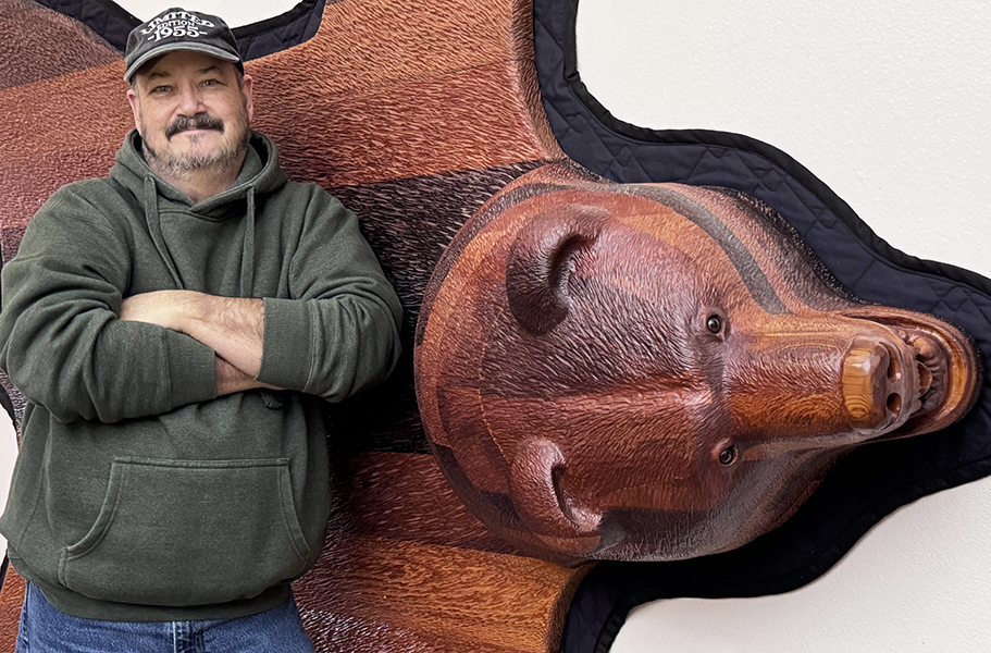 Keith standing alongside his bear rug carving